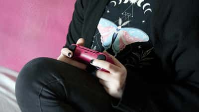 Person holding a PlayStation 5 DualSense controller while gaming