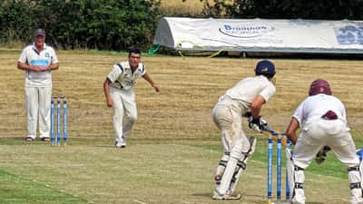 Cricket bowler in delivery stride at a summer match in Essex, England