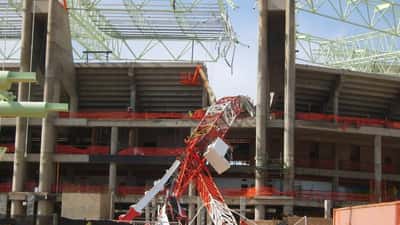 Grua tombada em obra de construção civil após acidente fatal, com estruturas metálicas colapsadas no local