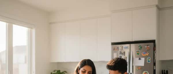 South Asian woman tutor and teenage student studying together at a kitchen table in a Toronto home