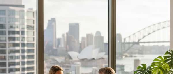 Wealth management consultation in a Sydney high-rise office with harbour light, adviser and client at a timber desk