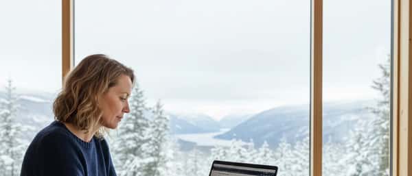 Nordisk kvinne som gjennomgår pensjonsdokumenter på en laptop ved et skrivebord i et norsk hjemmekontor