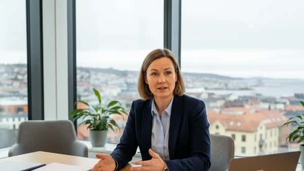 Norsk advokat i marineblå blazer forklarer kontrakt til klient i et Trondheim advokatkontor med byutsikt