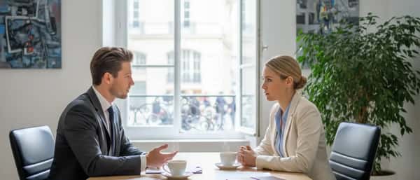 Mulher brasileira consultando uma advogada em escritório moderno de São Paulo, discutindo documentos sobre uma mesa de madeira