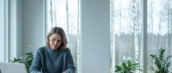 Nordisk kvinne gjennomgår finansdokumenter ved spisebord i lys skandinavisk stue