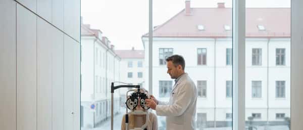 Norsk kvinne under synstest med foropter hos optiker i moderne klinikk i Oslo