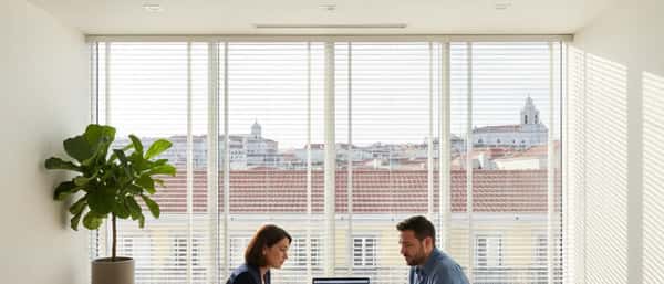 Consultora financeira portuguesa a analisar documentos com cliente num escritório moderno em Lisboa