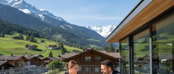 Consultation dans un cabinet d'avocat à Genève, cliente et avocat examinant des documents sur un bureau en bois