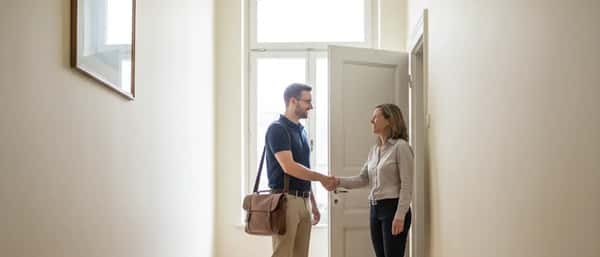 Informaticien arrivant chez un client dans un immeuble lausannois avec son sac pour ordinateur portable