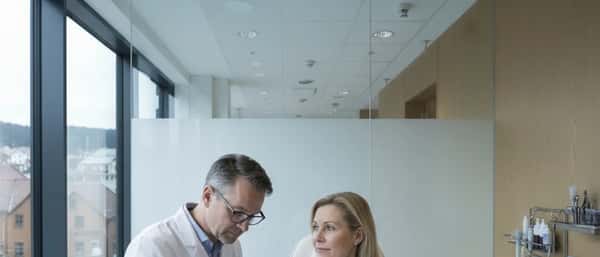 Hudlege undersøker pasientens arm med dermatoskop i en moderne norsk klinikk