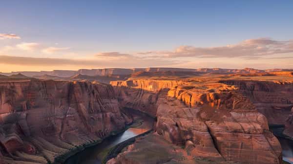 Sweeping panoramic view of the Colorado River canyon at sunrise in Arizona, red canyon walls and blue-green water