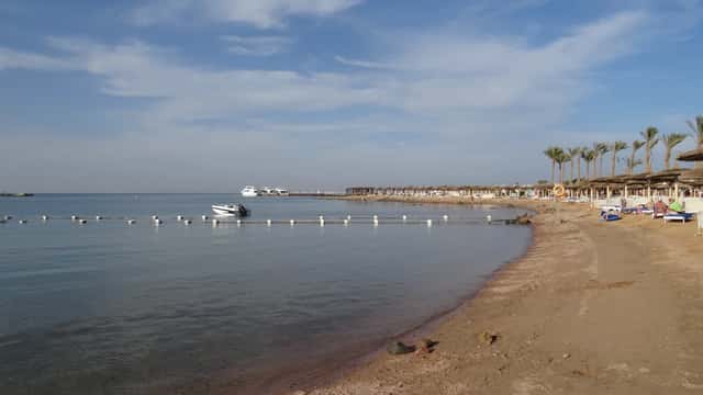 Red Sea beach resort in Egypt with turquoise water, tourists at the shoreline