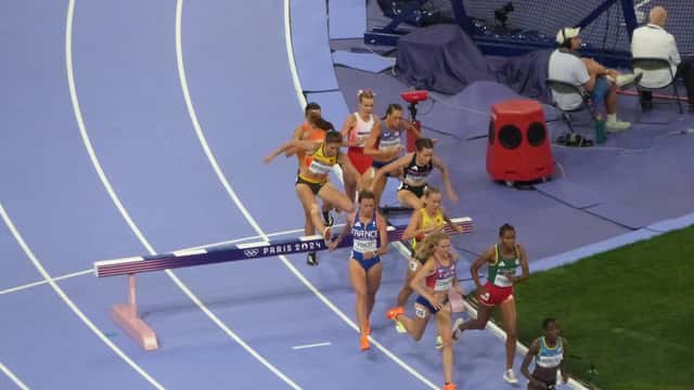 Nainen hyppää vesiestettä yleisurheilun estekilpailussa stadionilla