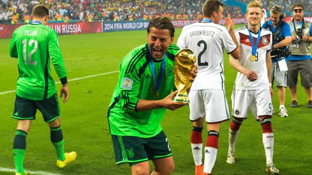 Jogador a segurar o troféu da Copa do Mundo FIFA, símbolo de prémios desportivos milionários