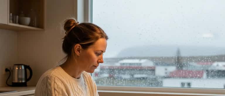 Íslensk kona skoðar orkugögn á spjaldtölvu við eldhúsborð í Akureyri, rafmagnsreikningur og kaffibolli á borðinu