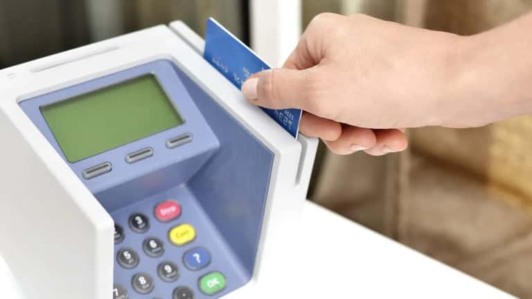 Customer tapping credit card on payment terminal at retail store counter