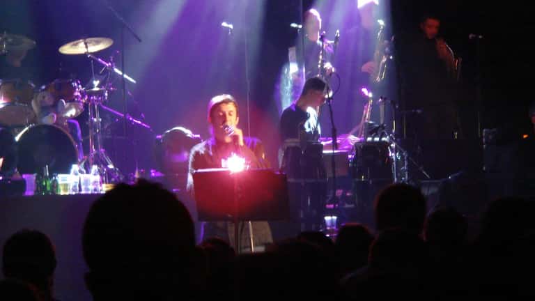 Paul Heaton performing live on stage with microphone during Beautiful South concert