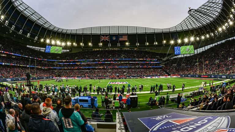Honor guard ceremony at a London NFL game with packed stadium crowd in background