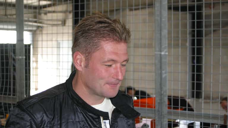 Jos Verstappen ao volante de um monolugar de corrida, ilustrando a carreira do pai de Max Verstappen