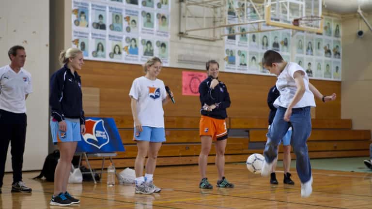 Professional soccer players speaking to students about soccer and academics at a school event