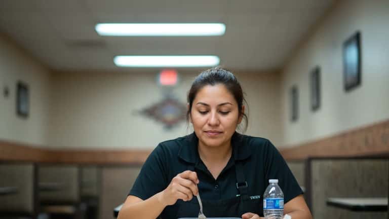 Latina restaurant worker eating lunch during a break at an empty table in Phoenix, Arizona