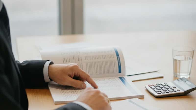 Mains d'un investisseur à Nantes comparant des brochures SCPI sur un bureau, calculatrice et documents financiers en arrière-plan