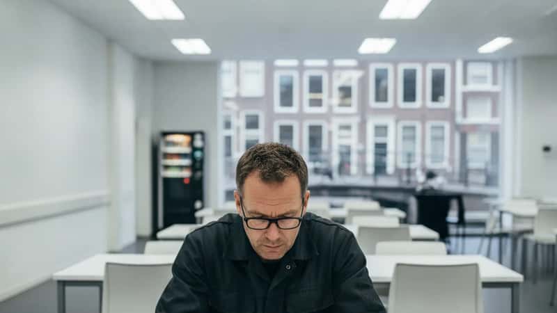 Nederlandse werknemer in Utrecht die zijn loonstrook bestudeert in een bedrijfskantine, geconcentreerde blik, financiële verificatie
