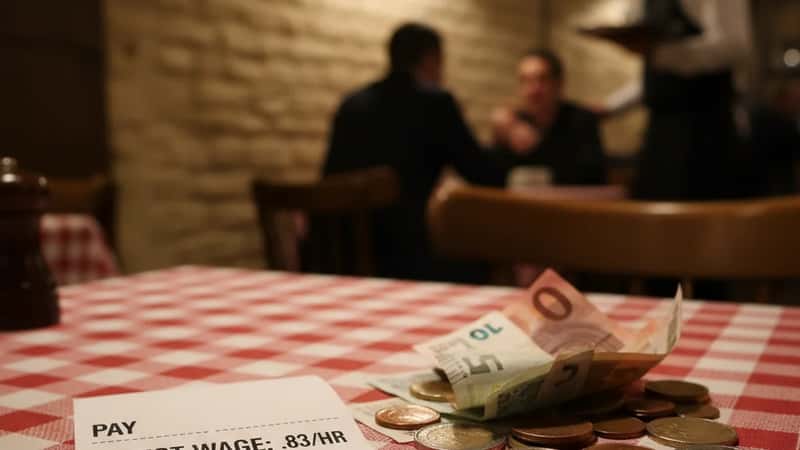 Pay stub showing tipped employee direct wage and cash tips on a Philadelphia restaurant tablecloth