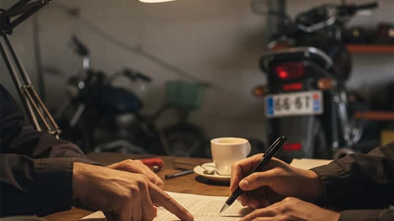 Grille salariale CCN Services de l'Automobile : deux personnes pointant les niveaux de classification sur un document imprimé dans un bureau de garage