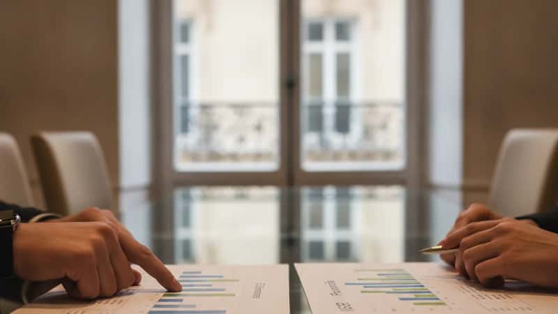 Mains de conseillers financiers pointant un graphique de performance ESG sur un document ISR lors d'une réunion à Nantes