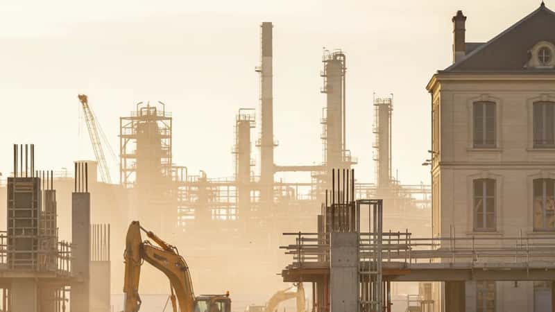 Baton Rouge construction workers in hard hats at industrial site with petrochemical facility background