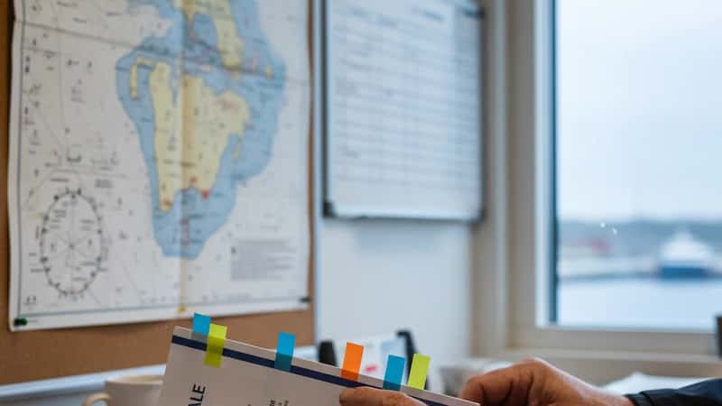 Sjøfolk i Stavanger tar gjennomgår kollektiv tariffavtale-dokumenter ved kaikontoret, med havneutsikt i bakgrunnen
