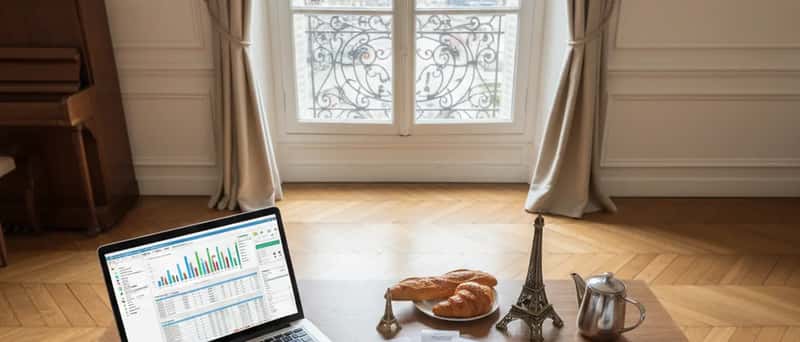 Tidy accountant desk with laptop showing accounting software, organised receipts, tea cup and reading glasses