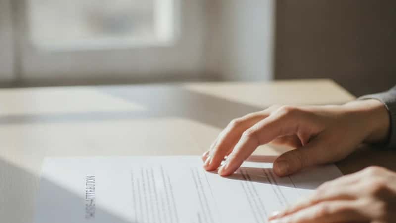 Femme lisant attentivement un acte de saisie-attribution posé sur un bureau à Strasbourg, lumière matinale douce sur des documents légaux
