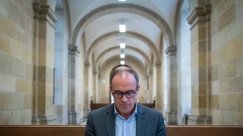 Homme de 50 ans en costume gris consultant des documents juridiques dans un couloir du palais de justice de Bordeaux