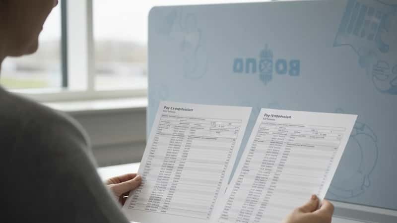 HR-medarbejder hos Rigspolitiet i Odense sammenligner lønskalaer fra OK26 ved sit skrivebord