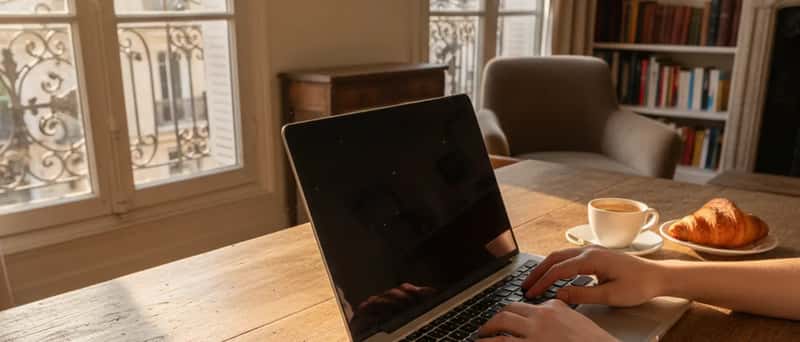 Mains tapant sur un ordinateur portable à côté d'un bail locatif et de clés sur un bureau en bois