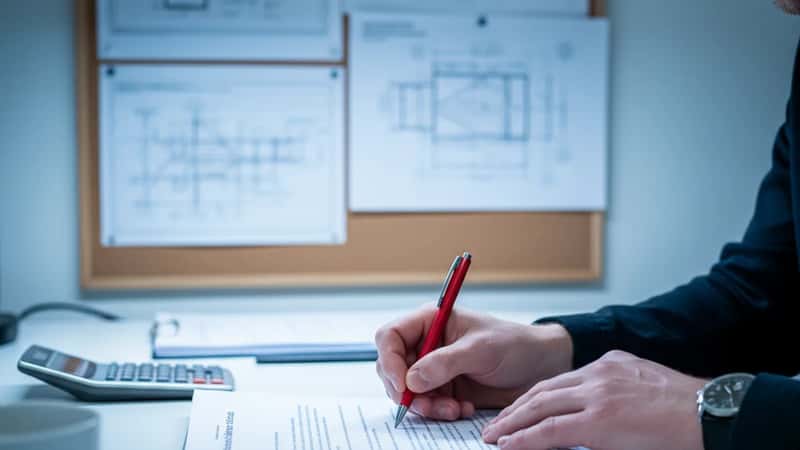 Norsk ingeniør annoterer tariffavtale dokumenter ved kontorpult i Tromsø – stillingsvern og oppsigelsesregler