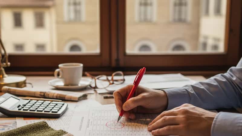 HR manager che annota le tabelle retributive CCNL con penna rossa su scrivania, Firenze