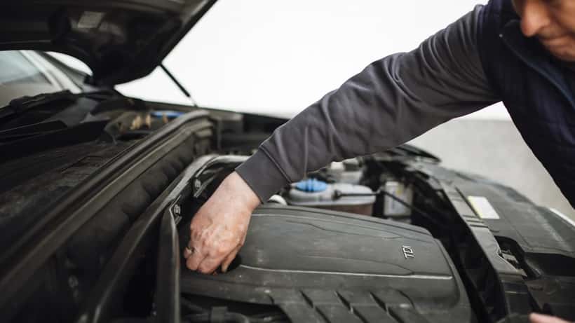 Mechanic performing routine maintenance and inspection on a car engine in a workshop