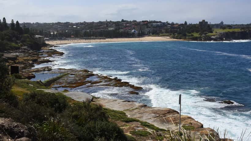 Coogee Beach Sydney with clear blue water and sandy shoreline, aerial view