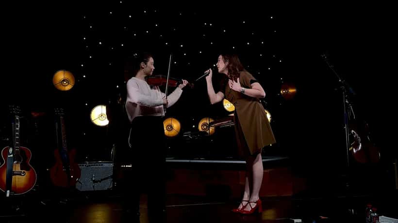 Laufey performing live on stage, singing into a microphone