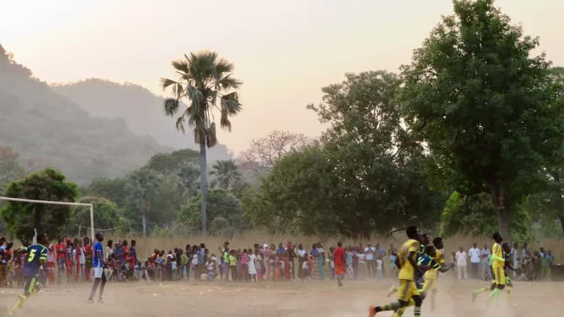 Match de football en plein air au Sénégal, joueurs en action sur terrain de terre battue