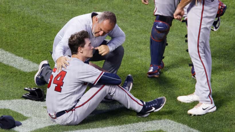 Baseball pitcher Max Fried being examined by athletic trainer on the field, arm health evaluation