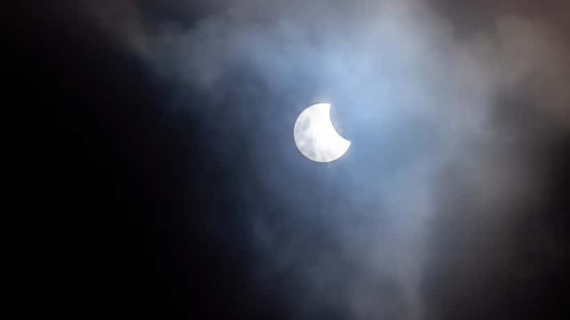 Partielle Sonnenfinsternis mit Wolken – die Sonne erscheint als heller Halbmond hinter Cirruswolken