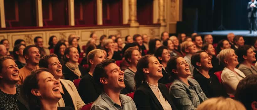 Nederlanders lachen samen in een theaterzaal bij warm schijnwerperslicht