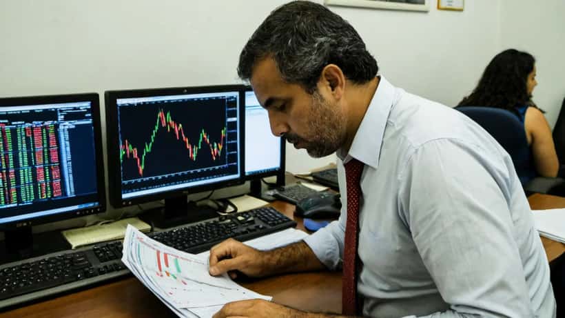 Consultor financeiro brasileiro analisando gráficos de queda do S&P 500 em escritório de São Paulo