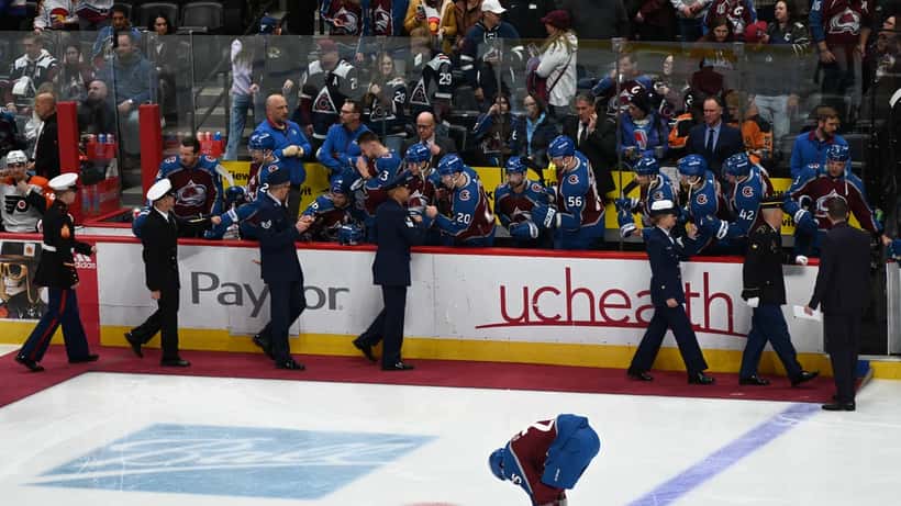 Colorado Avalanche coach on NHL bench during a game with protective barrier