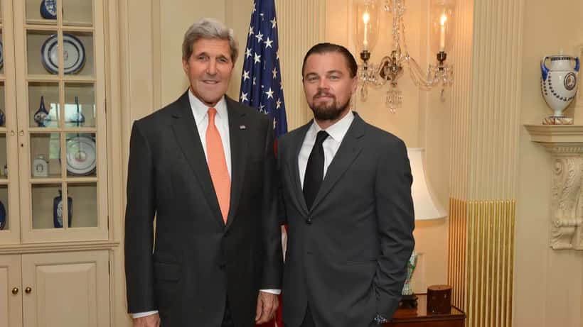 Leonardo DiCaprio keskustelemassa virallisessa tilaisuudessa puvussa hymyillen