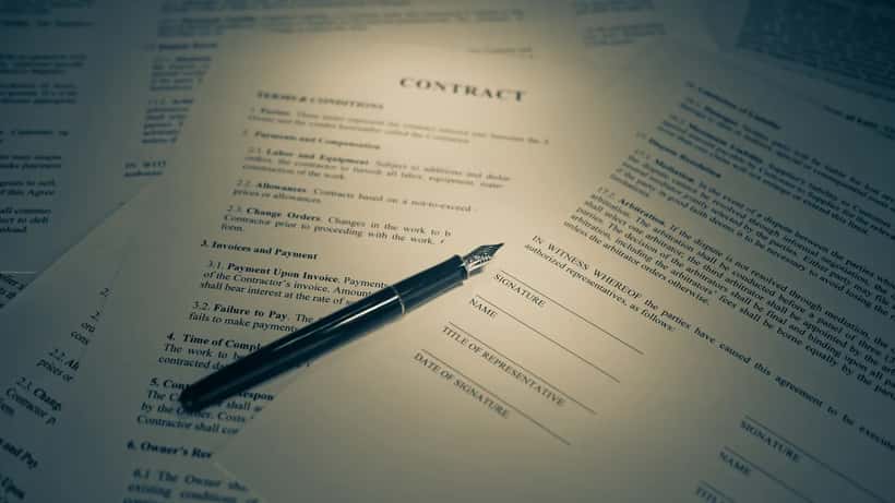 Close-up of a contract being signed at a desk